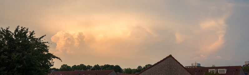 Panorama of a thunderstorm illuminated by the light of the setting sun