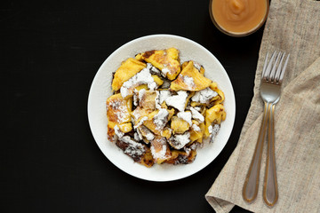 Homemade german Kaiserschmarrn pancake with apple sauce on a black surface, top view. Flat lay, overhead, from above. Copy space.
