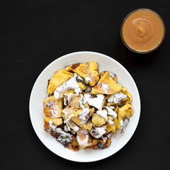 Homemade german Kaiserschmarrn pancake with apple sauce on a black surface, top view. Flat lay, overhead, from above. Close-up.