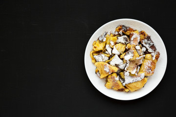 Homemade german Kaiserschmarrn pancake on a black surface, top view. Flat lay, overhead, from above. Copy space.