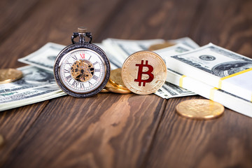The cryptocurrency Bitcoin coin. Gold coin. Vintage pocket watch stand on the background of bundles...