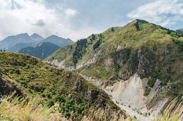 Steep green and rocky slopes of the mountains in Kazakhstan. At times, landslides and rockfalls occur
