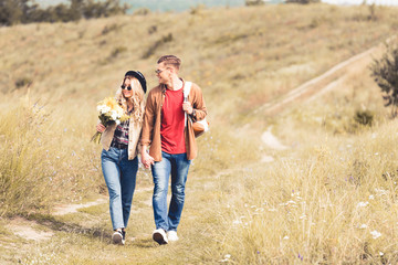 attractive woman with bouquet and handsome man smiling and holding hands