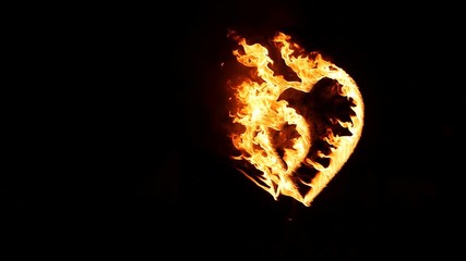 entertainment, fire performance, valentine day concept. on the metal support there is a big heart that all burning bright and smoking in the dark of night