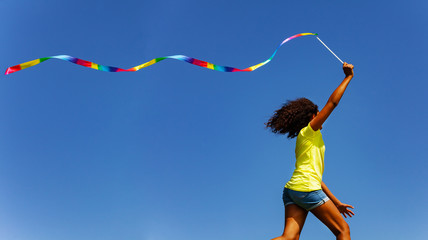 Profile view of a girl run with colorful ribbon