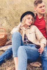 Naklejka premium handsome man looking away and attractive woman holding wine glass