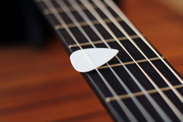 Fototapeta premium Guitar pick on the fingerboard of a brown guitar.