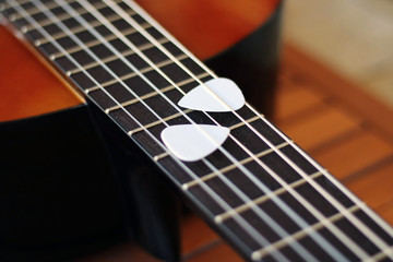 Guitar picks on the fingerboard of a brown guitar.