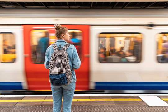 Rear view of young woman at subway station with incoming train