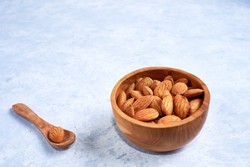 Almonds nut in a wooden bowl on a blue and white background