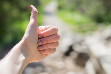 Fimale traveler showing thumb up against the backdrop of nature. Tourism concept. Copyspace