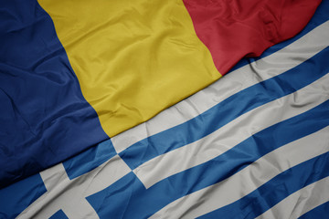 waving colorful flag of greece and national flag of romania.