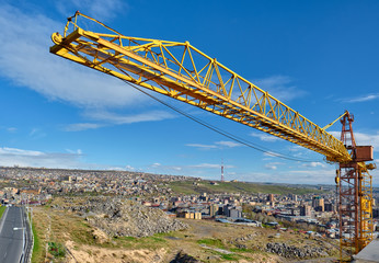 Fototapeta na wymiar Yellow construction jib crane tower against blue sky