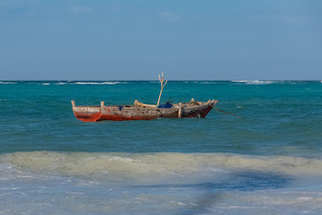 Naklejka premium Zanzibar in Tanzania, typical fishing boat on a beautiful beach with waves