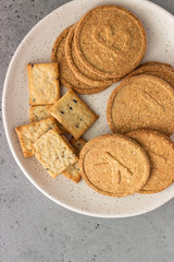 Thin crispy wholegrain crackers with seeds on grey concrete background. 