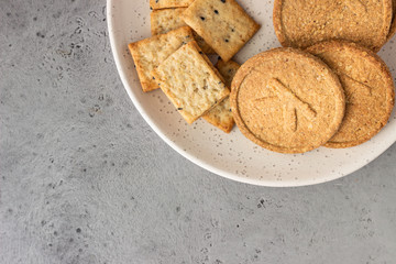 Thin crispy wholegrain crackers with seeds on grey concrete background. 