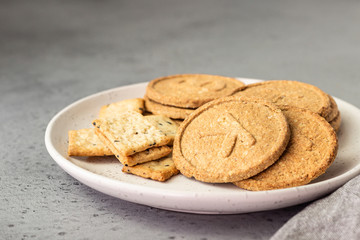 Thin crispy wholegrain crackers with seeds on grey concrete background. 