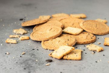 Thin crispy wholegrain crackers with seeds on grey concrete background. 