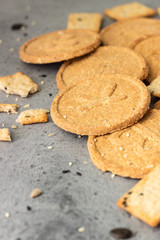 Thin crispy wholegrain crackers with seeds on grey concrete background. 