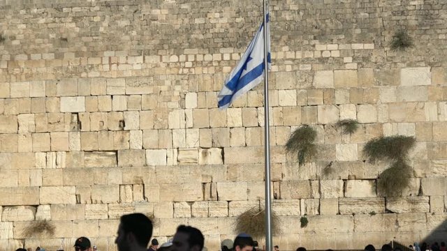 Israel flag fluttering in the wind in front of the holy Wailing Wall, one of the most sacred places to the Jewish people. 4K