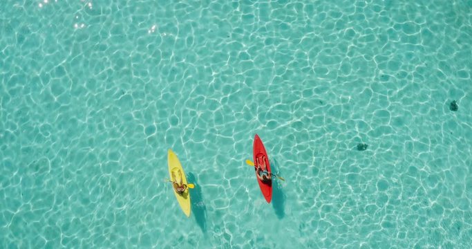 Aerial view of adventurous couple ocean kayaking together in pristine blue lagoon with sunny light textures refracting on the water surface, leisure kayaking tourism