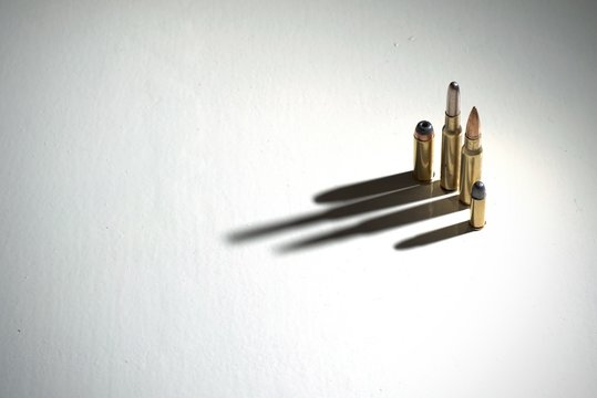 Crime family concept. Several bullets on a white surface with long, dramatic shadows.