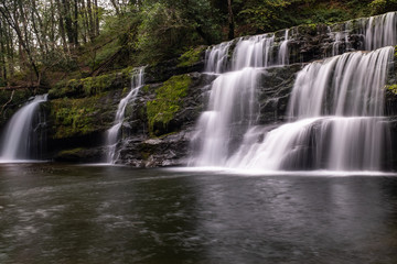 Fototapeta premium Low level view with a long exposure shot of waterfall, in the Brecon Beacons, Wales scenic waterfall with flowing water