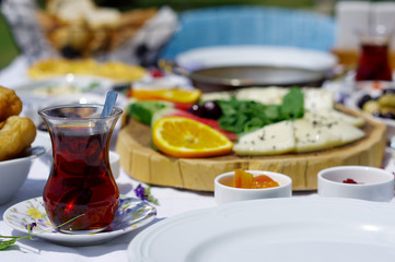 a glass of Turkish tea on a breakfast table next to some pastry and flowers