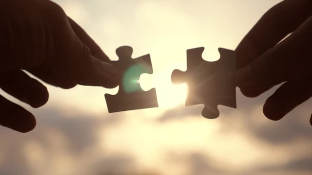teamwork business finance concept. male hands connect two puzzles silhouette against the sunset. symbol teamwork lifestyle of association and connection. strategy business