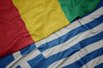 waving colorful flag of greece and national flag of guinea.