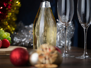 New Year's and christmas themed still life, Champagne bottle and flutes in focus, Decoration out of focus in boke.