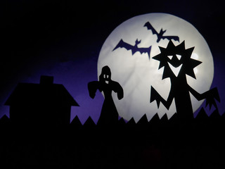 Dark Halloween season background with moon in the background and scary creatures silhouettes. Ghost, bats, and funny monster.