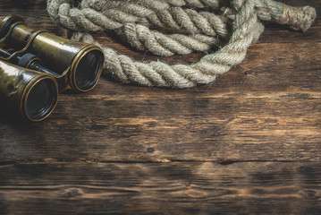 BInoculars and rope on a brown wooden table background.