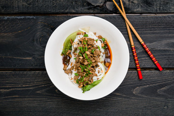 Dan Dan Noodles top view. Dan Dan Noodles is a spicy Szechuan cuisine dish commonly found in chinese street food. Ingredients include thick rice noodles, sichuan pepper, chili oil and ground pork.