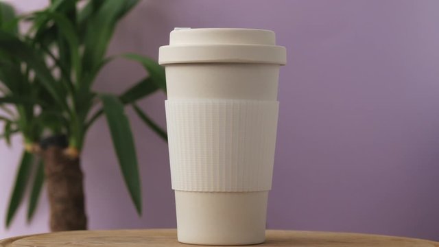 Reusable bamboo coffee cup rotating on the pink background