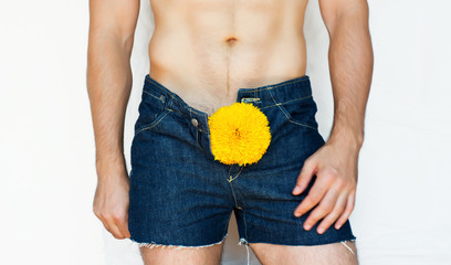 lower part of a man in shorts with a yellow sunflower in the intimate zone - Image