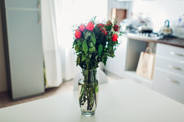 Bouquet of roses died in vase on kitchen. Wilted flowers left on table of modern apartment