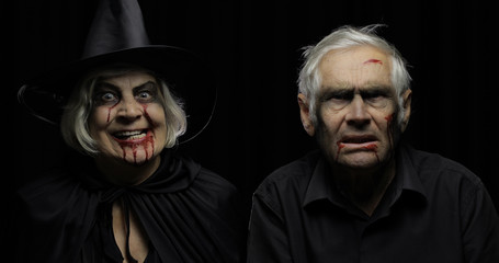 Elderly man and woman in Halloween costumes. Witch and zombie