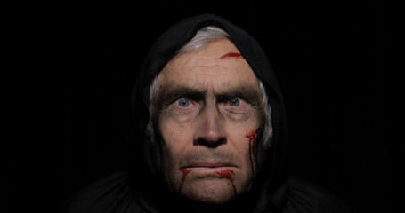Old executioner Halloween makeup and costume. Elderly man with blood on his face