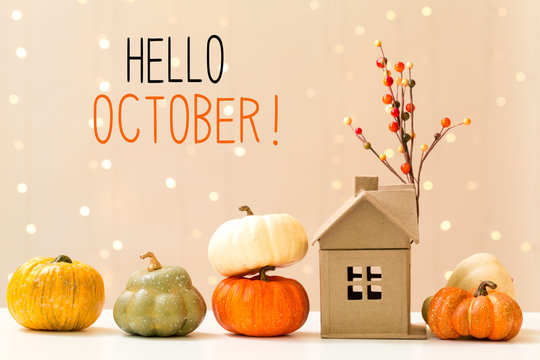 Hello October message with collection of autumn pumpkins with a toy house