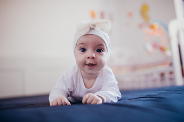 Beautiful baby girl crawling and rolling over in bed