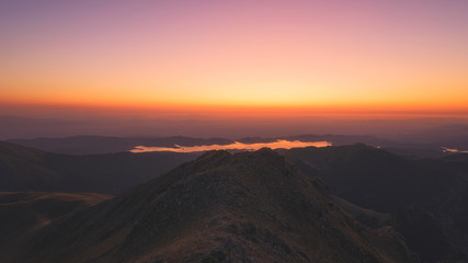 Burning dawn above Plastiras lake where the lake is glowing red from the sky
