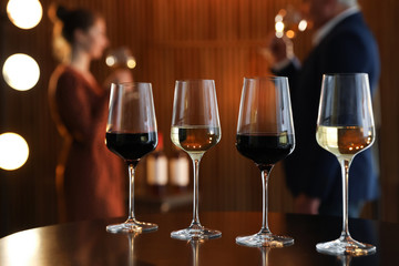 Glasses of different wines on table against blurred background