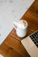 Lavender london fog tea latte with steamed milk and sugar on table in cafe next to gold laptop, brick background, copy space