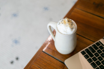 Lavender london fog tea latte with steamed milk and sugar on table in cafe next to gold laptop, brick background, copy space