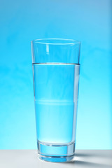 Glass of water on blue background. Refreshing drink