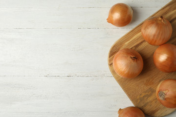Ripe onions on white wooden table, flat lay with space for text