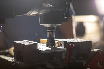 Worker cutting, grinding and polishing motorcycle metal part with cnc machine indoor workshop, close-up