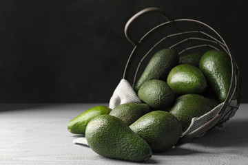 Delicious ripe avocados on grey wooden table against dark background