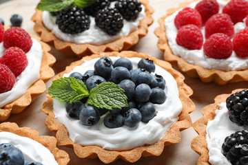 Many different berry tarts on table, closeup. Delicious pastries